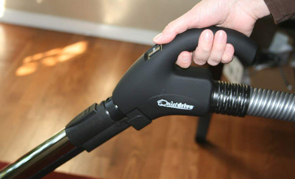 A person holding the handle of a central vacuum system attachment.