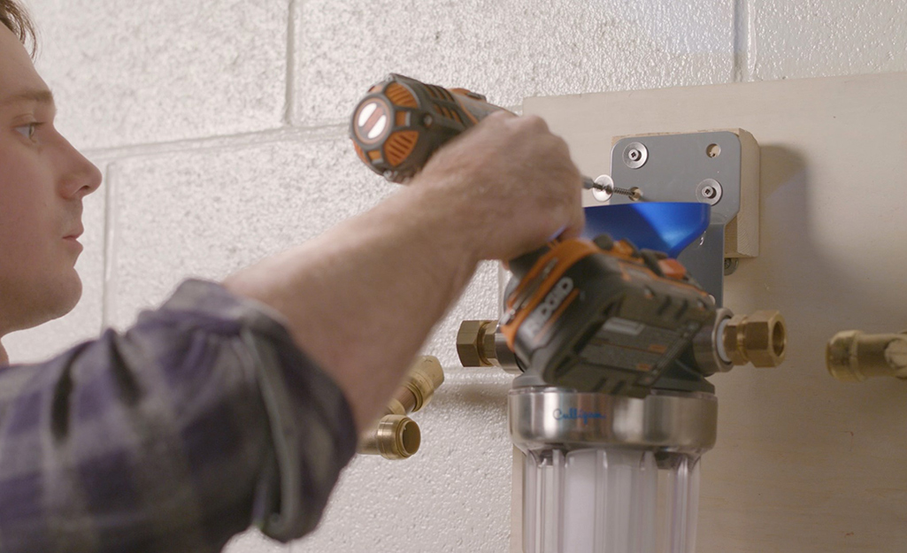 A person installing a whole-home water filter.