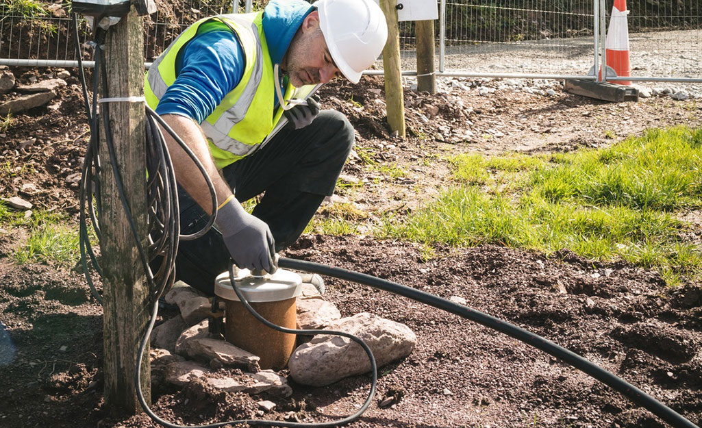A man installing connections to a well pump casing.