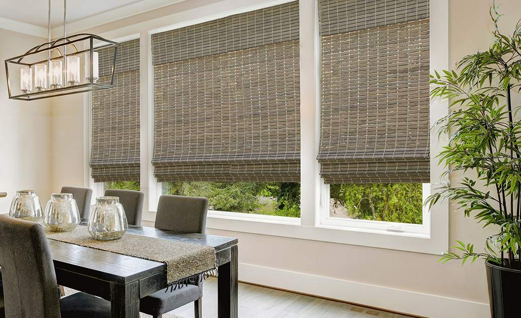 Woven window shades hanging in a dining room.