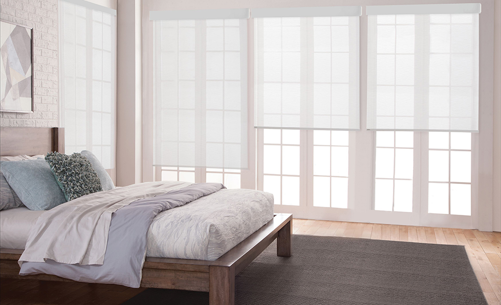 White roller shades installed in a bedroom.