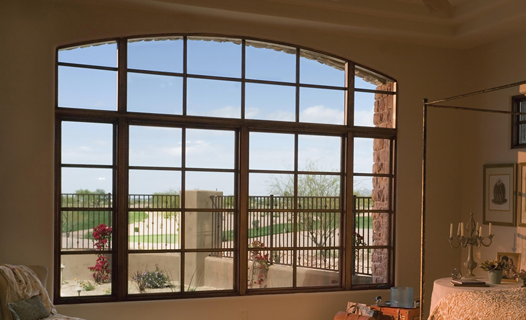 Windows in wooden frames overlook a fenced in courtyard.