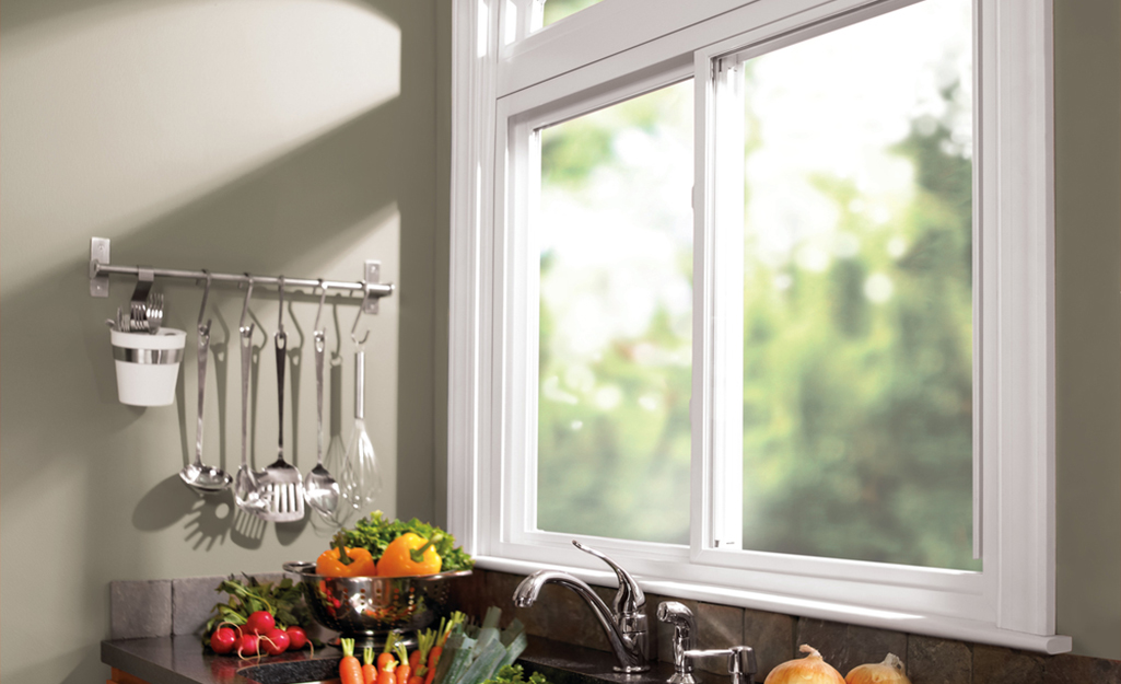 Light shines through a sliding glass window over a kitchen sink.