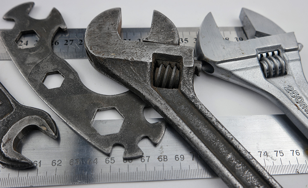 Several different types of wrenches placed next to a ruler.