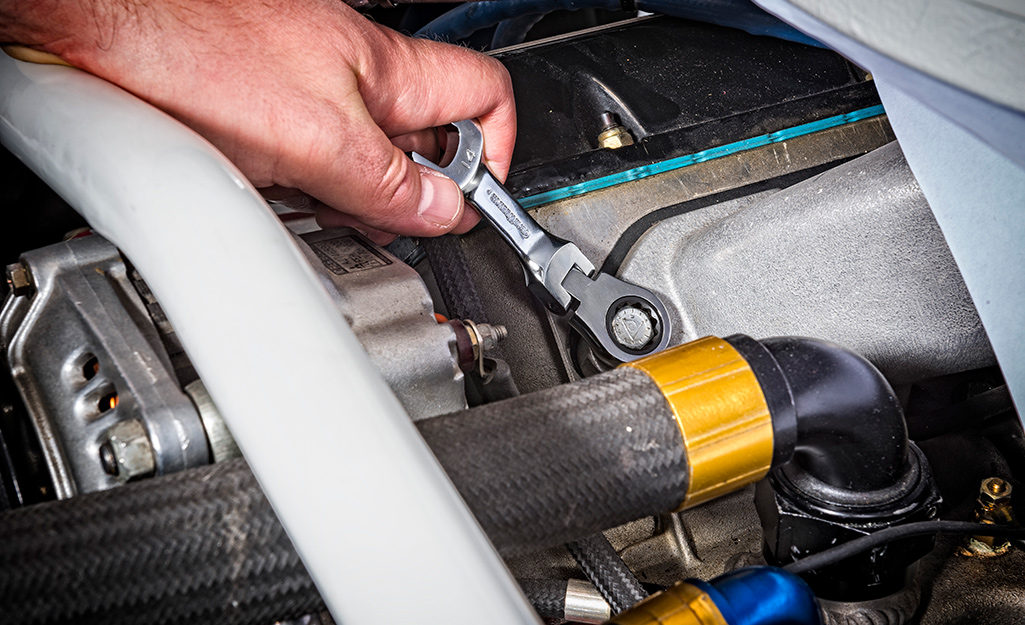 Someone working on a hose with a combination wrench.