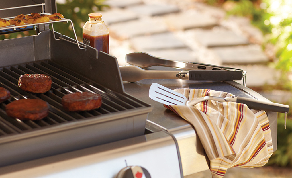 A spatula and tongs resting on a grill's side shelf. A spatula and tongs resting on a grill's side shelf.