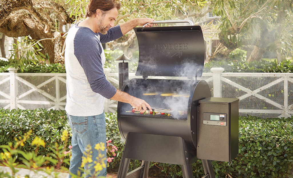 A person tending to food cooking on a pellet grill. A person tending to food cooking on a pellet grill.