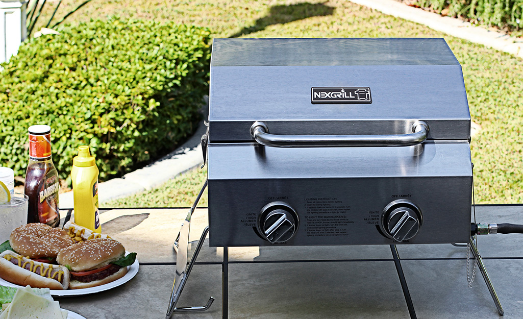 A portable grill sitting on a table on a patio. A portable grill sitting on a table on a patio.