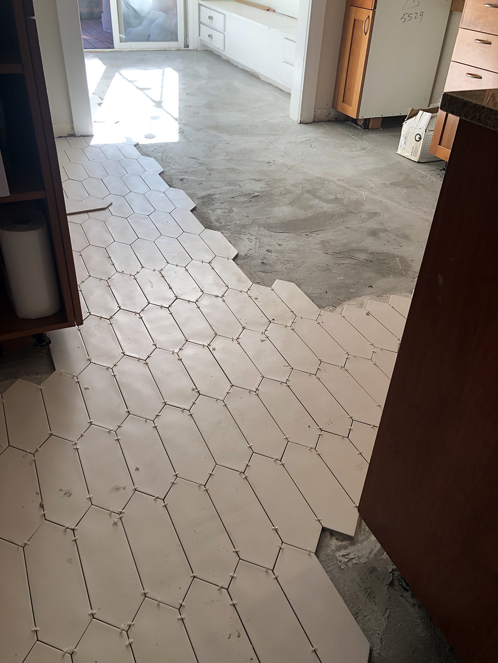 A kitchen floor with white picket tiles being installed.