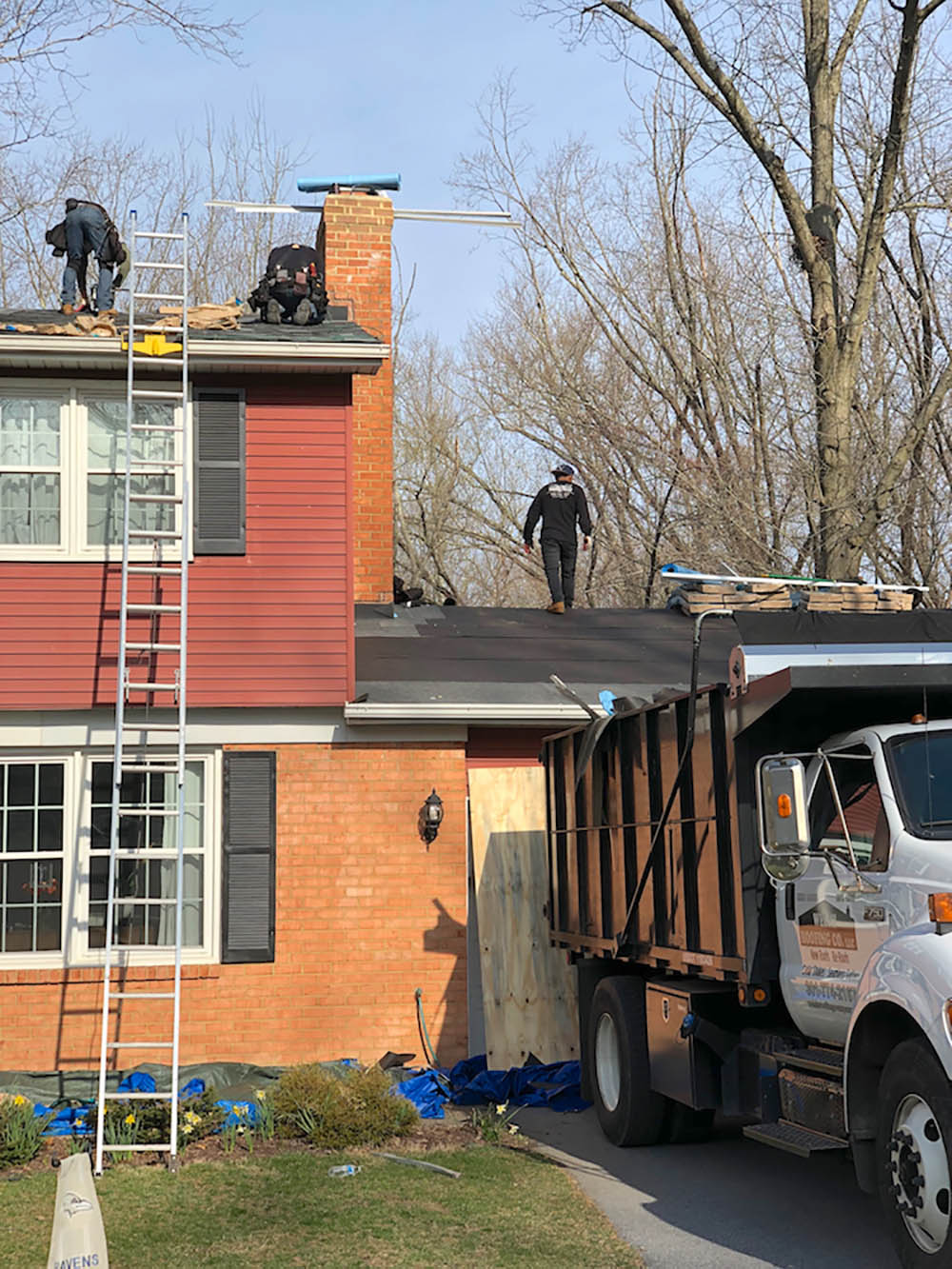 Three men replacing a roof on a two-story home.