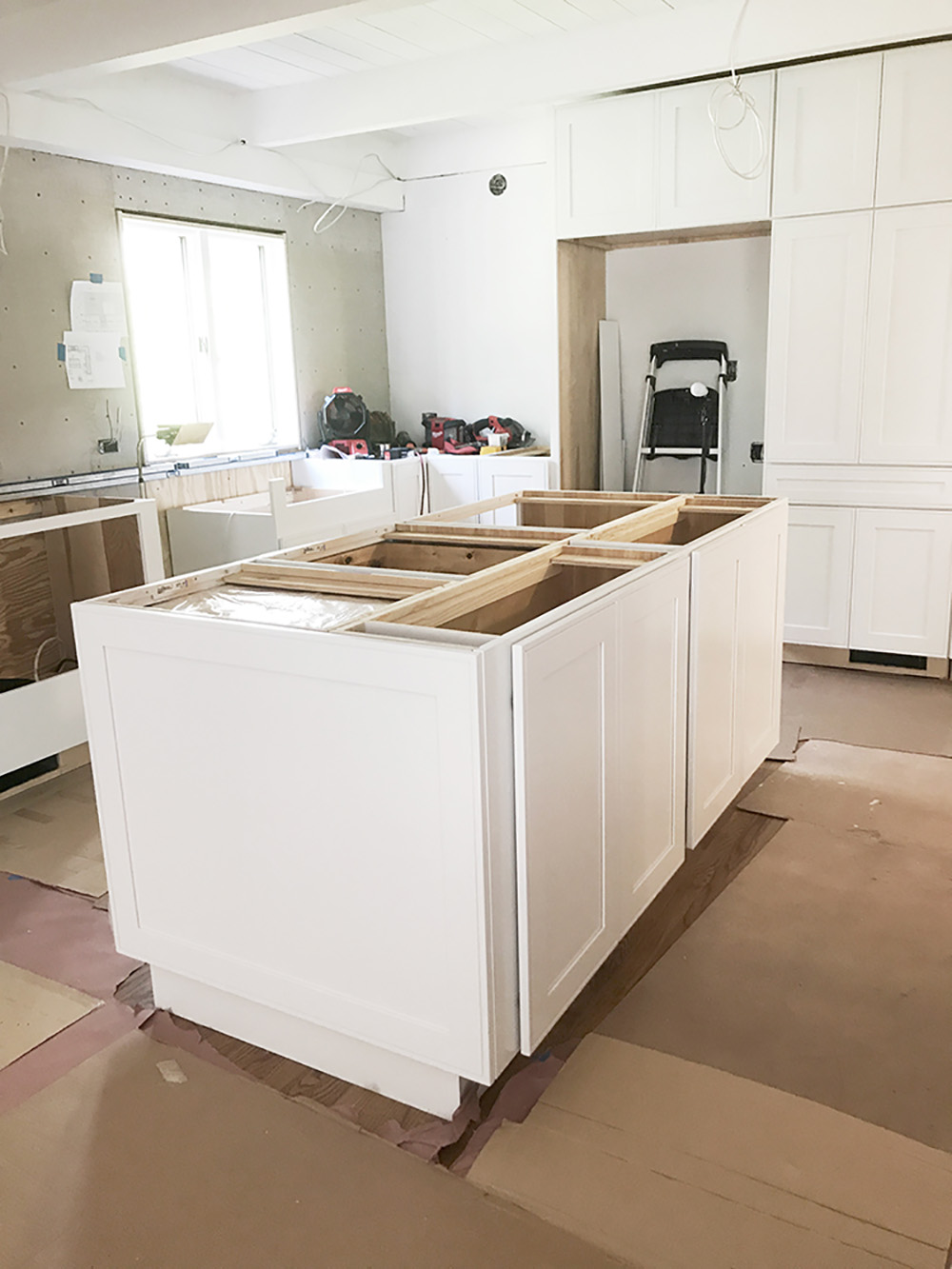 A kitchen with white cabinets partially installed.