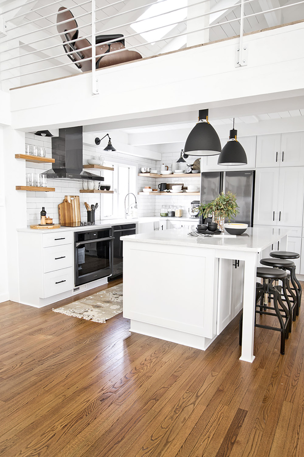 An updated kitchen with black appliances, open shelving, and white cabinets.