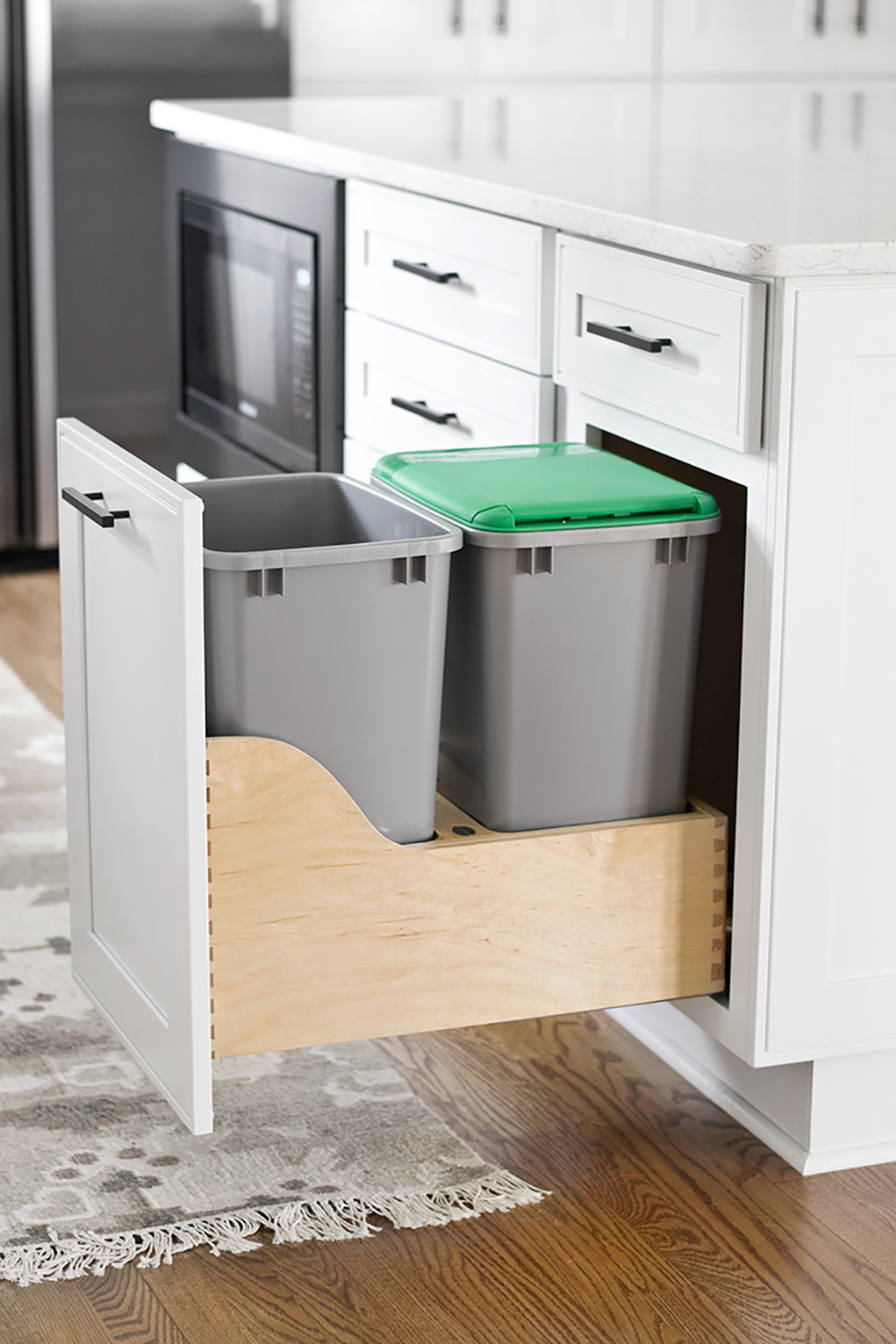 A roll out cabinet drawer reveals hidden trash and recycling bins.