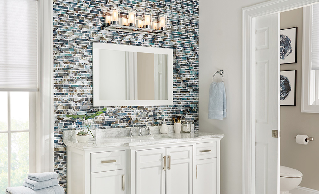A white vanity and mirror with a colorful backsplash.
