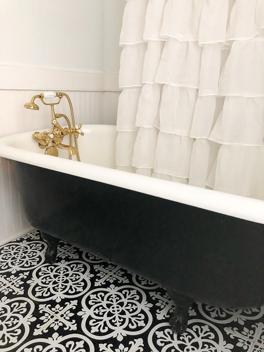 A bathroom with a decorative tile floor and a clawfoot bathtub.