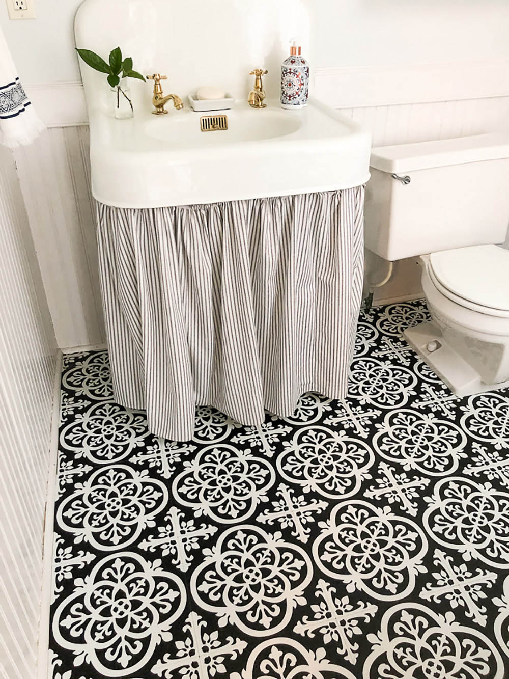 A bathroom with white and black decorative flooring and a cast-iron apron front sink.