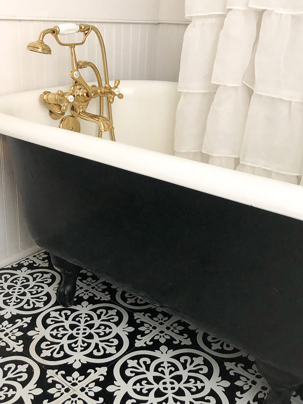 A black and white clawfoot bathtub with a brass faucet.