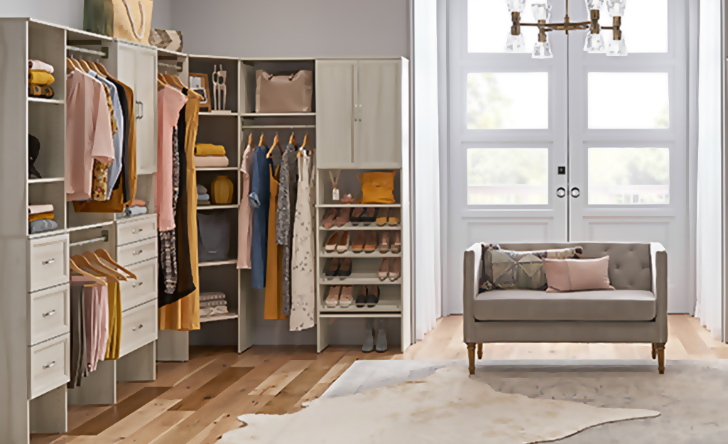 A small sofa sits on one side of a large walk-in closet, with hanging clothes, shelves and drawers on the other