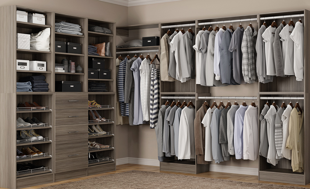 Clothes hang on rods on one side of a large gray walk-in closet, with shelves of shoes on the other.