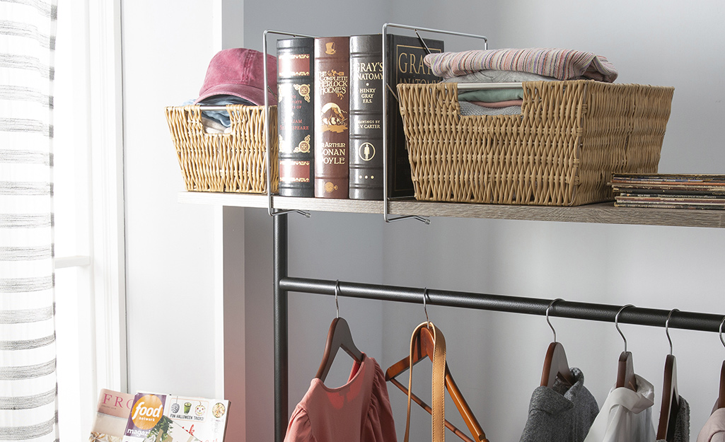 Brown baskets provide storage for folded items on a shelf above a clothing rod.