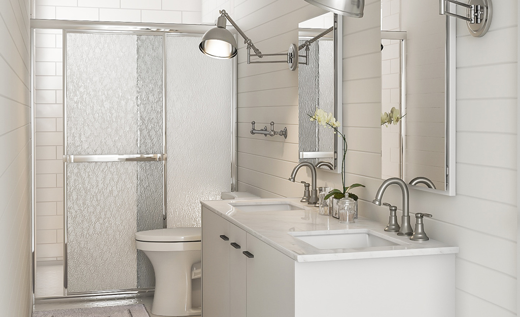 A walk-in shower with sliding, textured glass doors in a white bathroom.