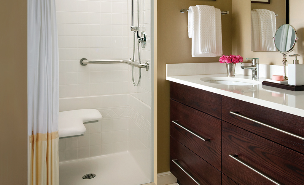 A walk-in shower with a built-in bench, grab bar and flexible shower head.