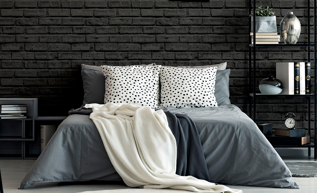 A black brick wall offsets a blue accessories in a bedroom.