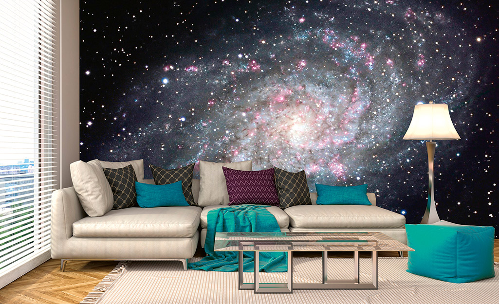 A large, space mural used as wall art behind a sofa.