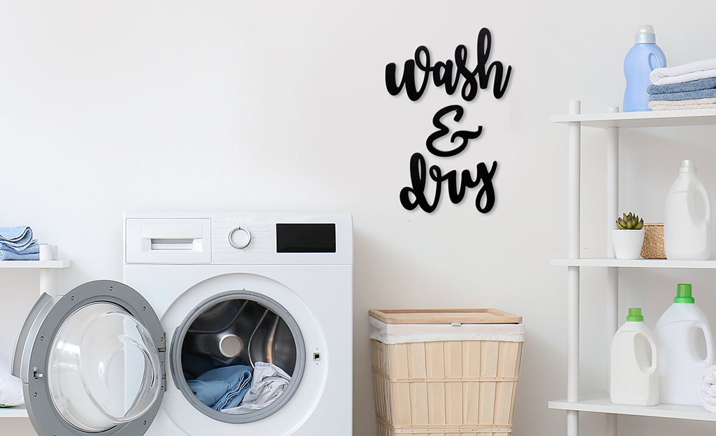A sign reading "Wash & Dry" used as wall art over a washing machine.