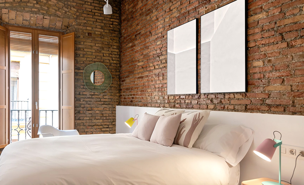 A bedroom with brick style wall paneling installed on the walls..