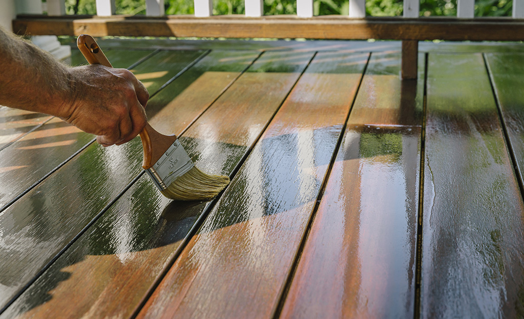 Person applying sealer to a wood deck.