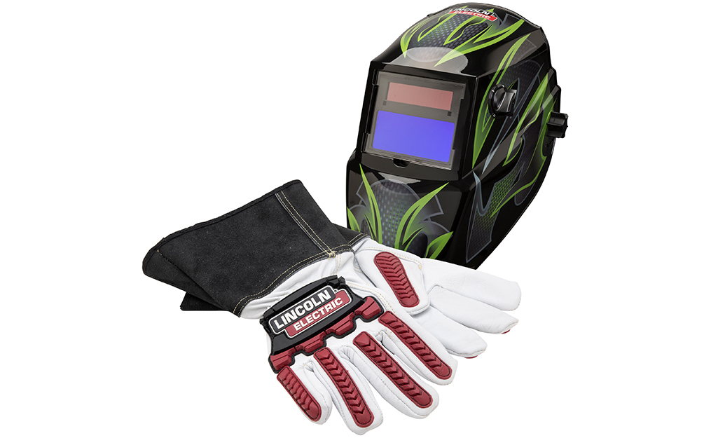 A welding helmet and welding gloves sit on a white background.