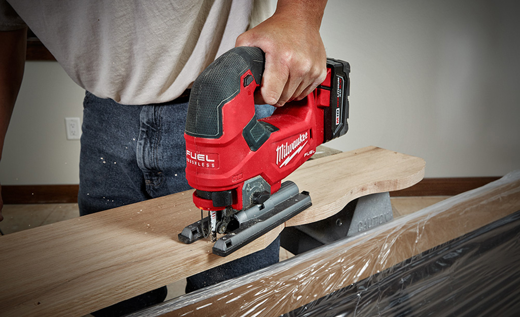 A person uses a miter jig while cutting a piece of wood.