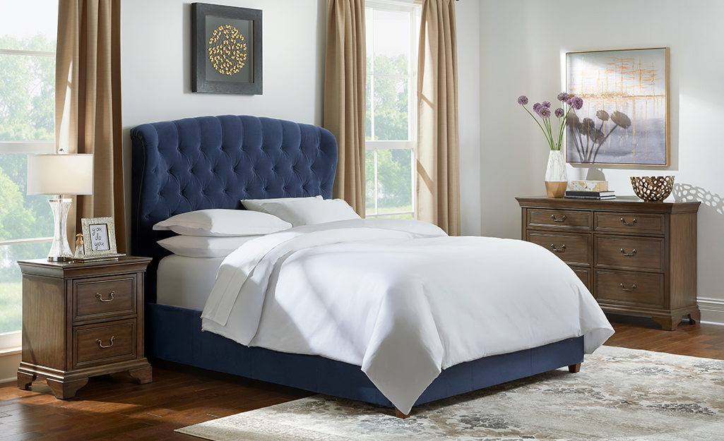 A master bedroom featuring a bed with a blue headboard and white bedding.
