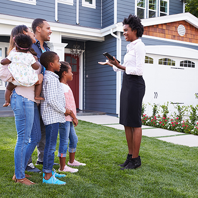 A family meets with a realtor outside of a home.