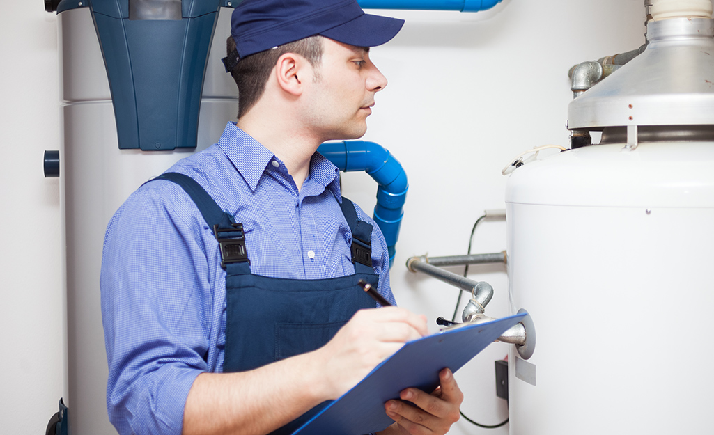 A man holding a clipboard looks at a water heater.