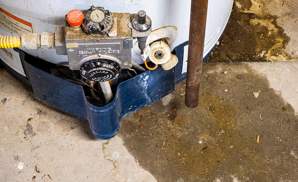 Water leaking out of a water heater makes a wet spot on the concrete floor.