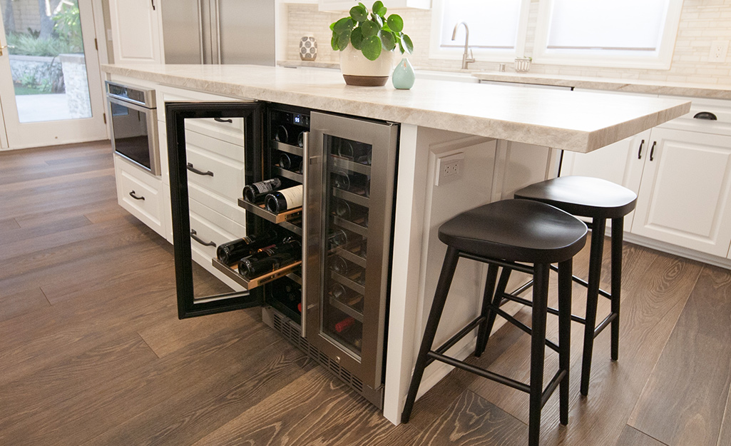 A stainless steel built-in wine cooler installed in a kitchen island.