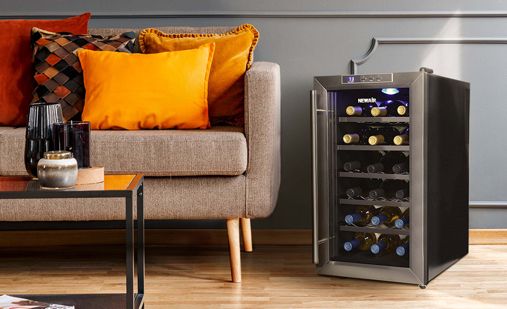 A free standing wine cooler sits near a sofa.