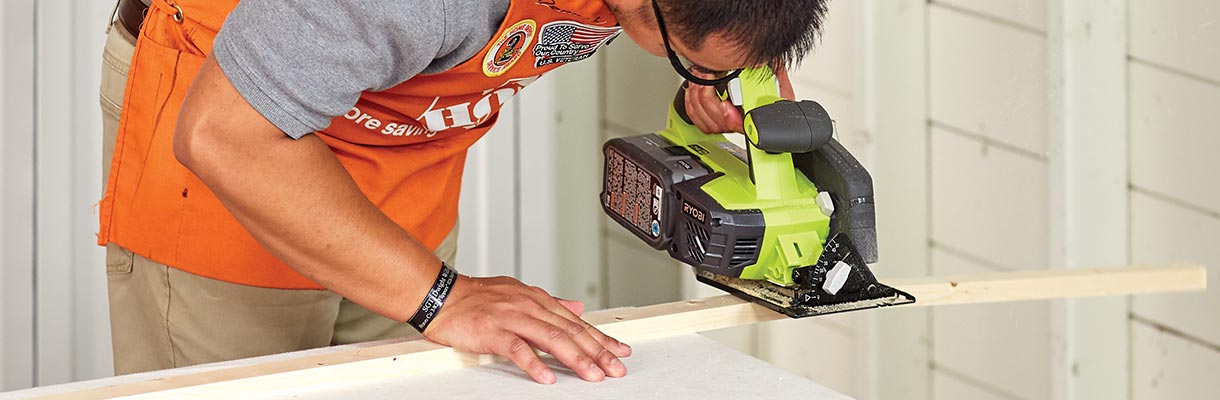 A man cutting a circular saw to cut a piece of wood. A man cutting a circular saw to cut a piece of wood.
