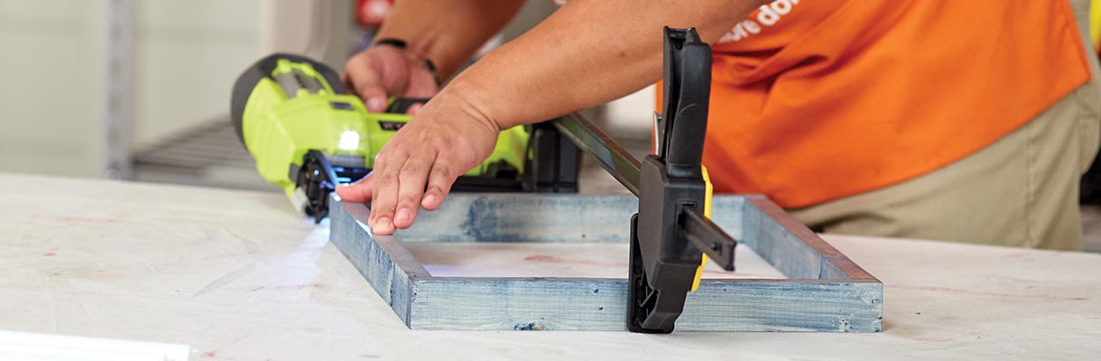 A man drilling pieces of a blue wood frame together. A man drilling pieces of a blue wood frame together.