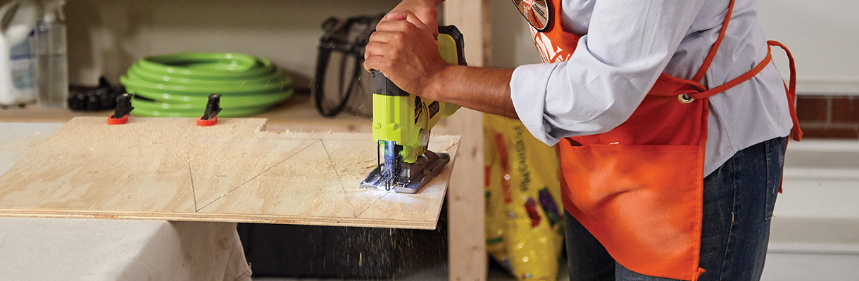 Man using a jigsaw to cut triangle shapes in plywood. Man using a jigsaw to cut triangle shapes in plywood.