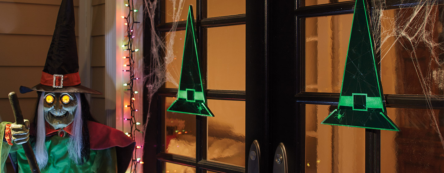 Two wooden witches hats hanging on a front door among assorted Halloween decor. Two wooden witches hats hanging on a front door among assorted Halloween decor.
