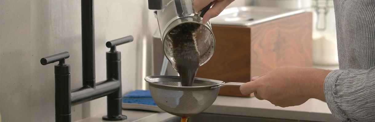A person straining used coffee grounds from a french press coffee maker. A person straining used coffee grounds from a french press coffee maker.