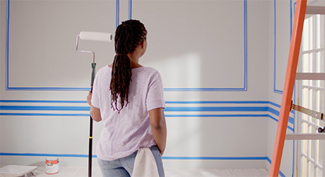 A woman taping off a room in preparation for painting. A woman taping off a room in preparation for painting.
