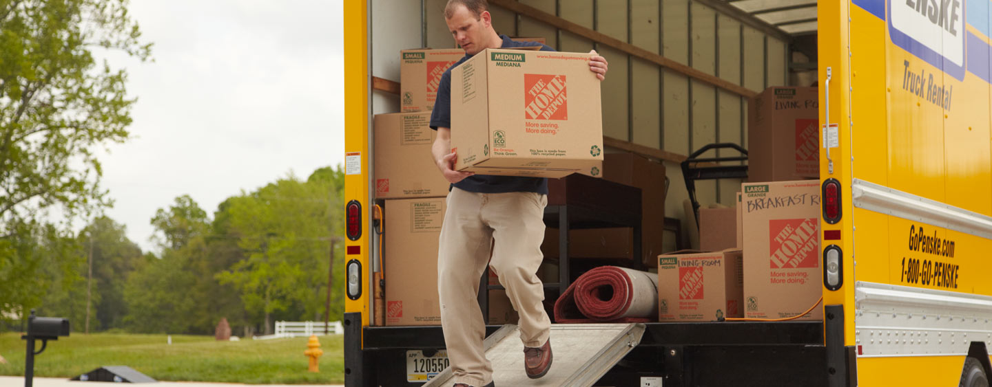 Man carrying a moving box from The Home Depot out of a Penske rental truck Man carrying a moving box from The Home Depot out of a Penske rental truck