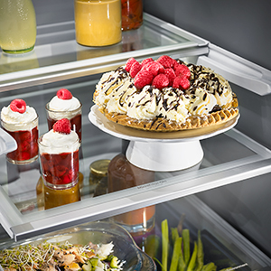 Four desserts standing on a glass refrigerator shelf. Four desserts standing on a glass refrigerator shelf.