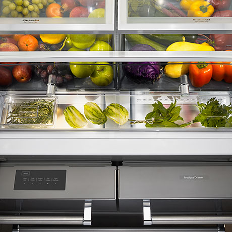 Crisper drawers filled with fruits and vegetables with fresh herb storage visible underneath. Crisper drawers filled with fruits and vegetables with fresh herb storage visible underneath.