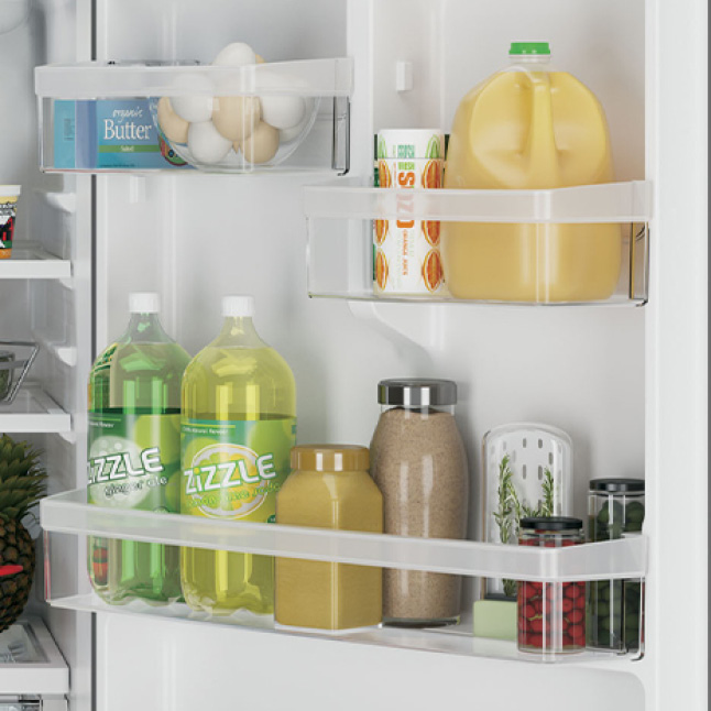 A variety of bottles, boxes, and jars of food and drink are neatly contained in the spacious door bins of the bottom freezer refridgerator.