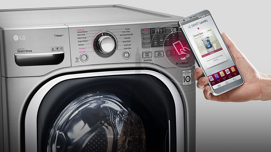 Close up of a hand holding a smartphone with the Smart Diagnosis App open in front of an LG washing machine